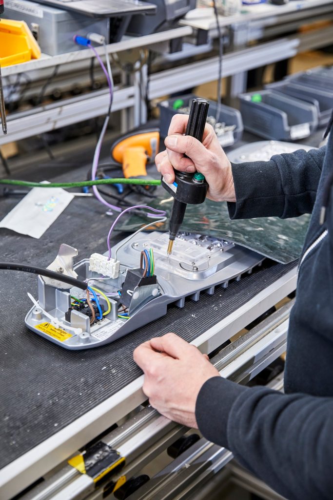Close-up of hands fitting a light engine with a torque driver on the INDO production line