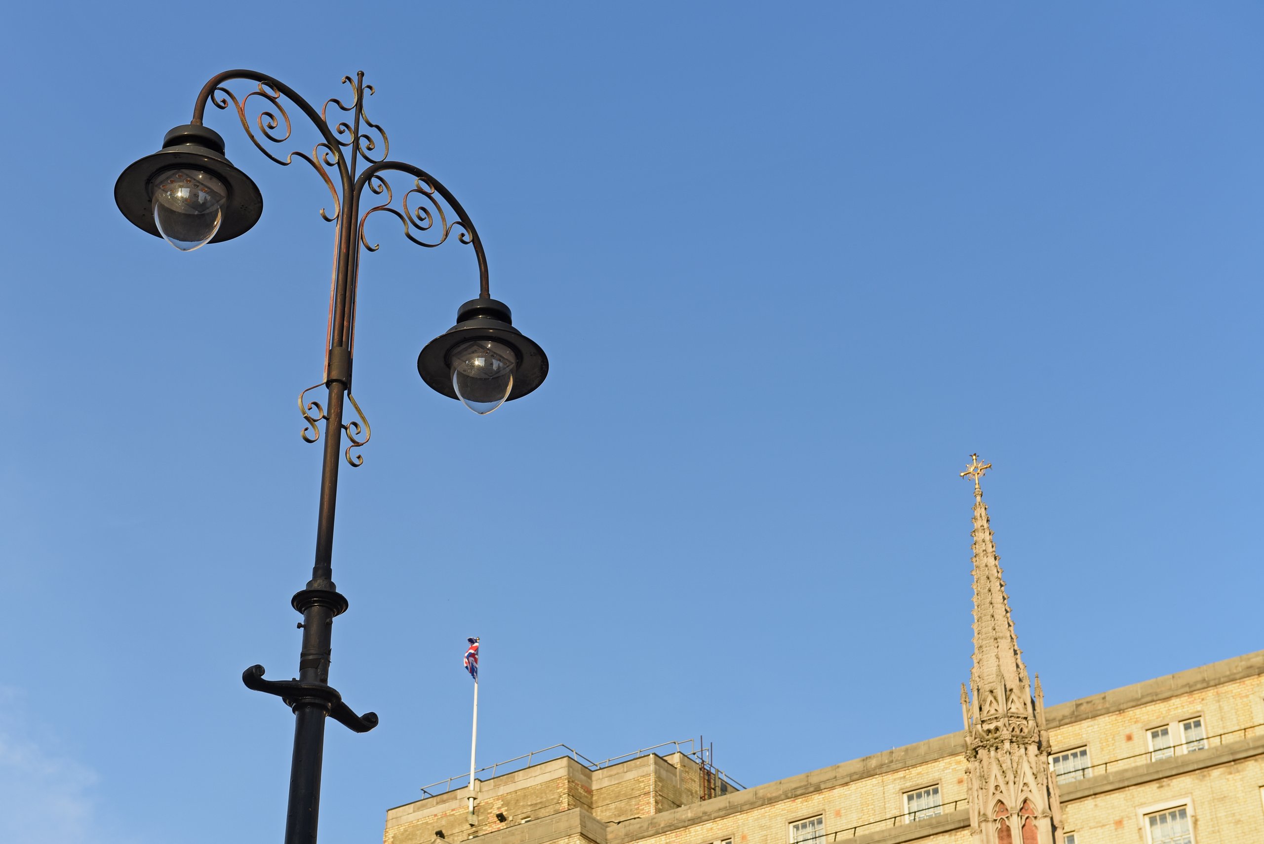 Twin-arm heritage street lantern against a blue sky in Westminster